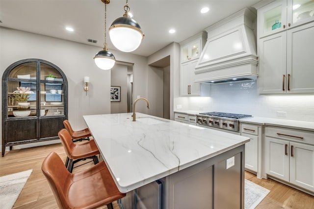 kitchen featuring visible vents, premium range hood, a sink, backsplash, and stainless steel gas stovetop