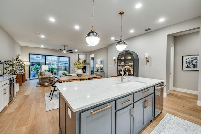 kitchen featuring stainless steel dishwasher, beverage cooler, a sink, light wood-style flooring, and gray cabinetry