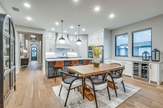 dining area with wine cooler, recessed lighting, light wood-type flooring, and visible vents