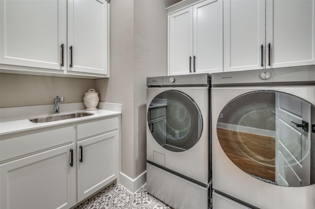 laundry room with cabinet space, washing machine and dryer, a sink, and tile patterned flooring