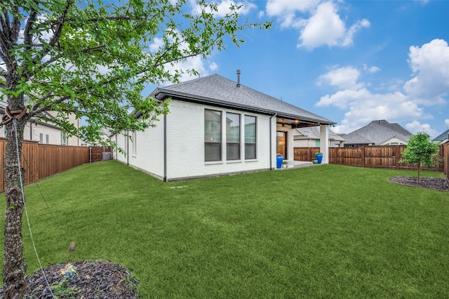 rear view of property with a yard, brick siding, a fenced backyard, and roof with shingles