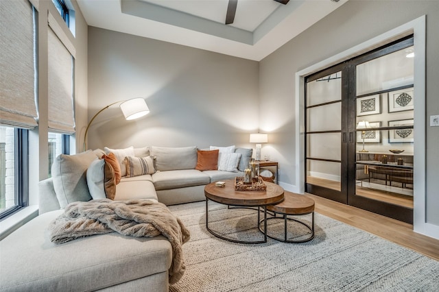 living room featuring baseboards, ceiling fan, a healthy amount of sunlight, and wood finished floors