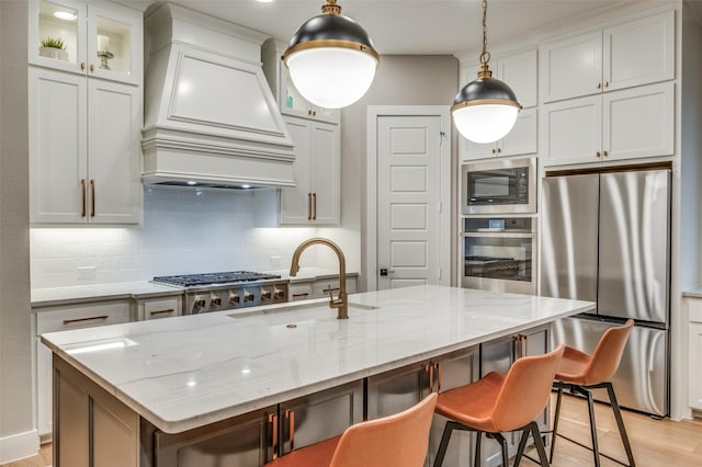 kitchen featuring a kitchen breakfast bar, custom range hood, a sink, backsplash, and stainless steel appliances