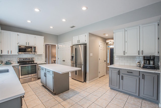kitchen featuring stainless steel appliances, gray cabinetry, decorative backsplash, and visible vents