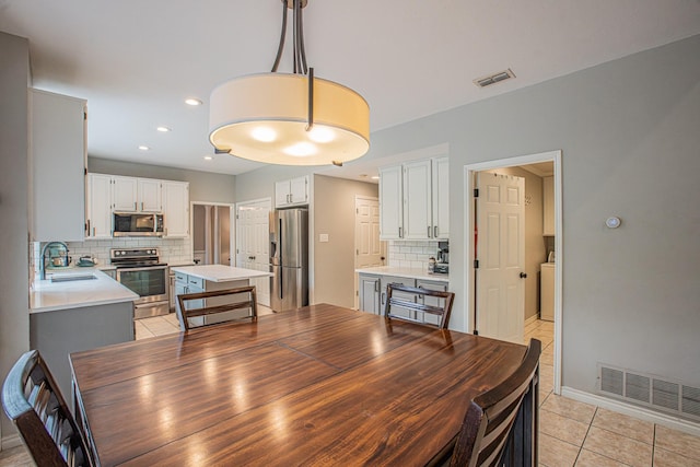 dining space featuring light tile patterned floors, baseboards, washer / clothes dryer, and visible vents