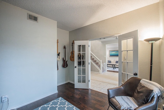 living area with visible vents, a textured ceiling, wood-type flooring, and french doors