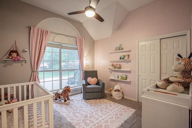 carpeted bedroom featuring a closet, lofted ceiling, baseboards, ceiling fan, and a crib