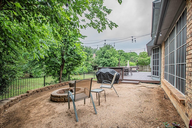 view of patio with a fenced backyard, an outdoor fire pit, and a deck