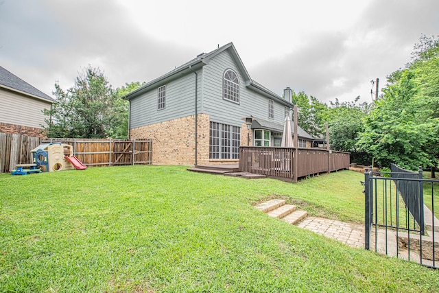 back of house featuring brick siding, a fenced backyard, a lawn, and a deck