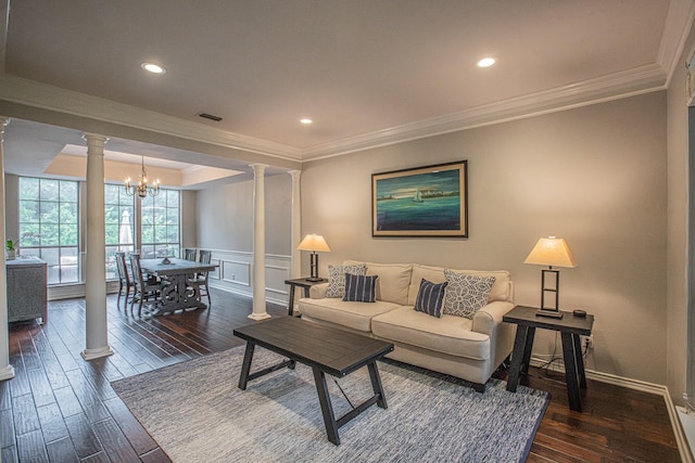 living area with ornate columns, ornamental molding, dark wood-style flooring, and a chandelier
