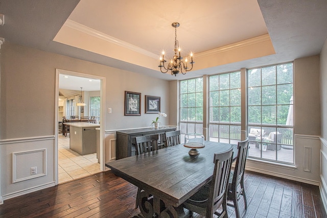 dining area featuring wood-type flooring, crown molding, a notable chandelier, and a tray ceiling