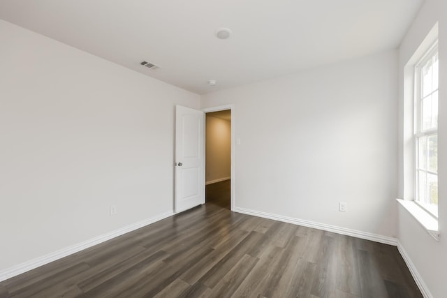 empty room featuring baseboards, visible vents, and dark wood-type flooring