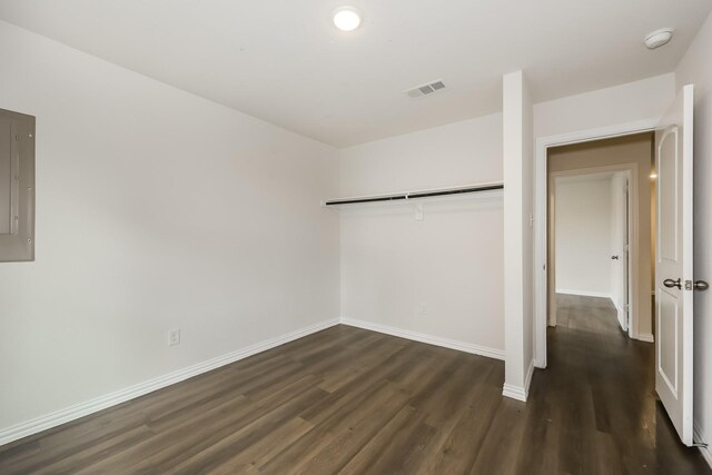unfurnished bedroom with visible vents, a closet, dark wood-style flooring, baseboards, and electric panel