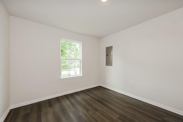 spare room featuring baseboards, electric panel, and dark wood finished floors