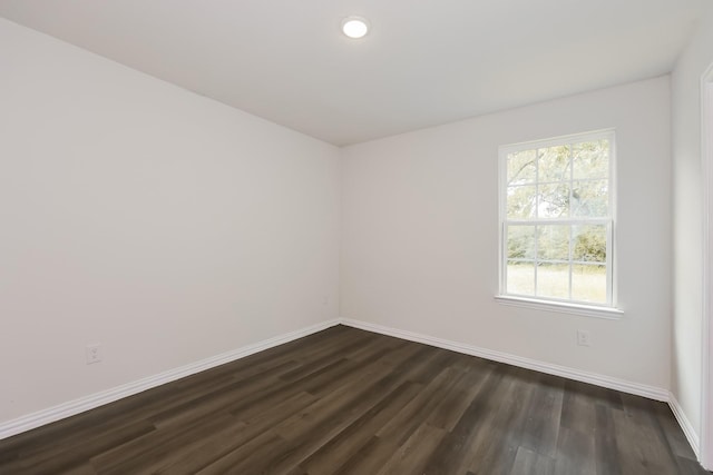 empty room featuring recessed lighting, baseboards, and dark wood-type flooring