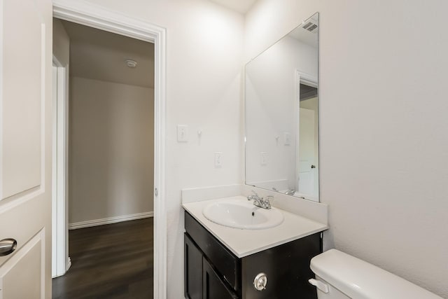 bathroom with vanity, toilet, wood finished floors, and visible vents