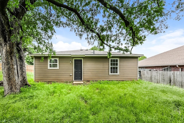 rear view of property featuring fence and a lawn