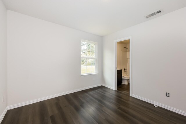 spare room with baseboards, dark wood-style floors, and visible vents