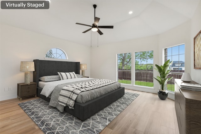 bedroom featuring ceiling fan, wood finished floors, vaulted ceiling, and multiple windows