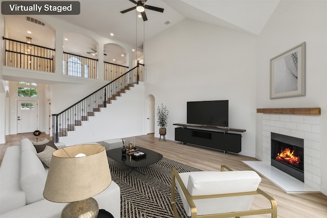 living room with a ceiling fan, high vaulted ceiling, visible vents, and wood finished floors