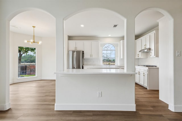 living room with light wood-style floors, arched walkways, recessed lighting, and visible vents