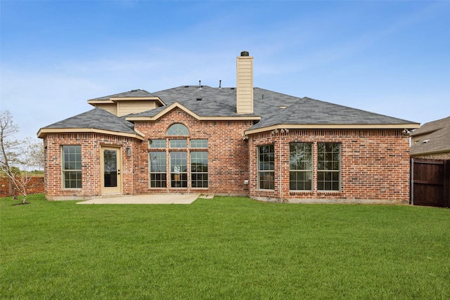 rear view of house with a lawn, fence, a patio, and a chimney