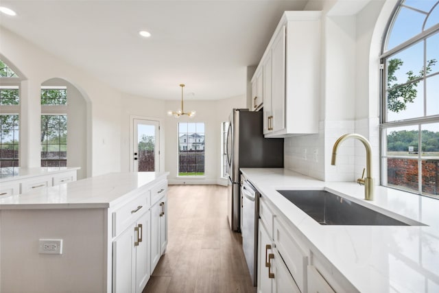 kitchen featuring an inviting chandelier, recessed lighting, white cabinets, tasteful backsplash, and a sink