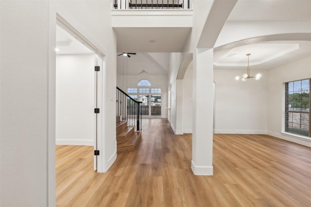 unfurnished living room featuring a ceiling fan, a brick fireplace, high vaulted ceiling, baseboards, and light wood-style floors