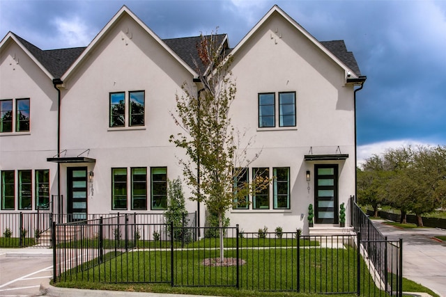 view of front facade featuring a fenced front yard, a front yard, and stucco siding