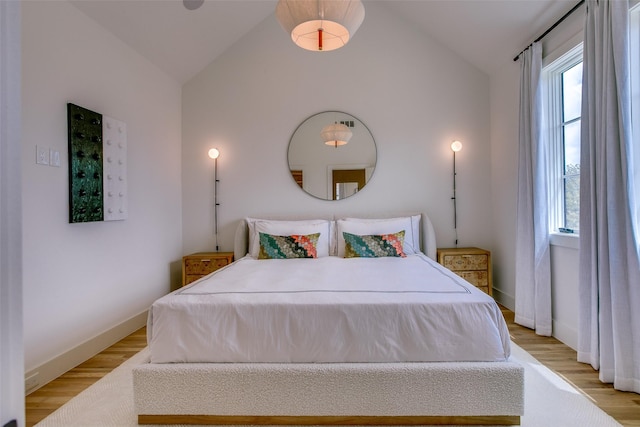 bedroom featuring baseboards, light wood-style flooring, and lofted ceiling
