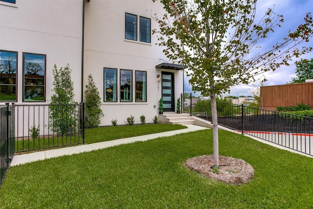 view of front of home with fence, stucco siding, and a front lawn
