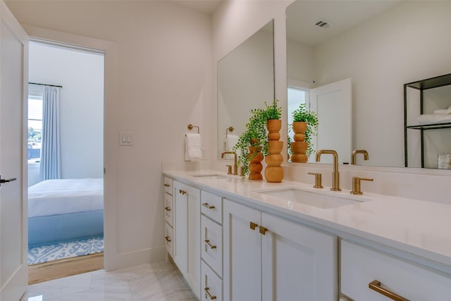 ensuite bathroom featuring a sink, baseboards, double vanity, and visible vents