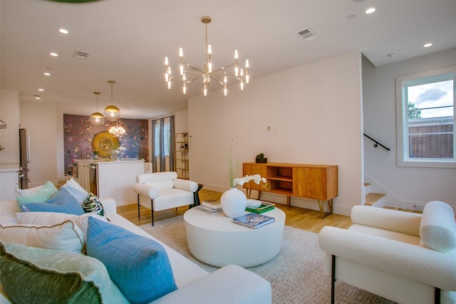 living area featuring visible vents, light wood finished floors, baseboards, and a chandelier