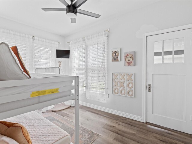 bedroom with baseboards, a ceiling fan, wood finished floors, and multiple windows