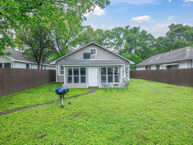 rear view of property featuring a fenced backyard, board and batten siding, and a yard