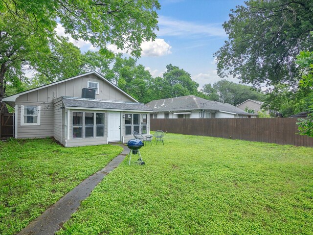 back of property with board and batten siding, a yard, and a fenced backyard