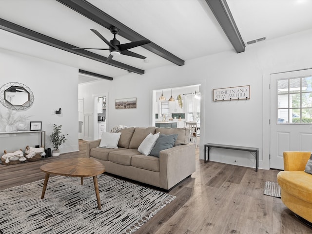 living room with beamed ceiling, ceiling fan, visible vents, and wood finished floors