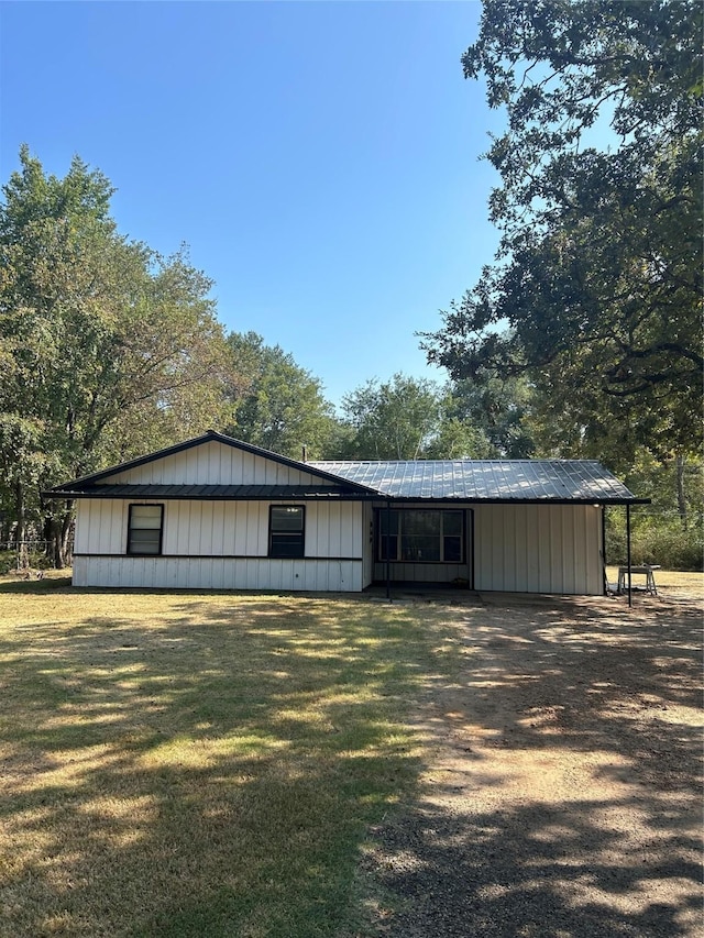 111 Circle Dr, Bogata, TX 75417 - view of front facade featuring dirt driveway, an attached carport, a front yard, metal roof, and view of wooded area