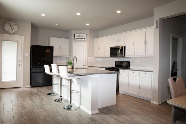 1714 Cecil Crest Ln, Forney, TX 75126 - kitchen with gas stove, white cabinets, stainless steel microwave, light wood finished floors, and black fridge
