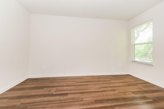 spare room featuring baseboards and wood finished floors