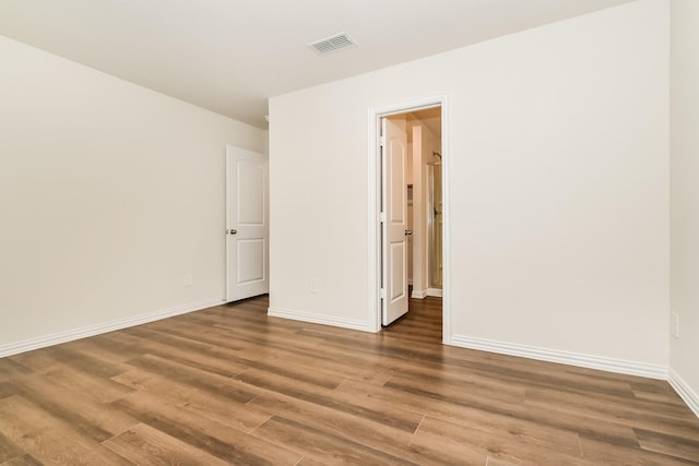 unfurnished room featuring baseboards, wood finished floors, and visible vents