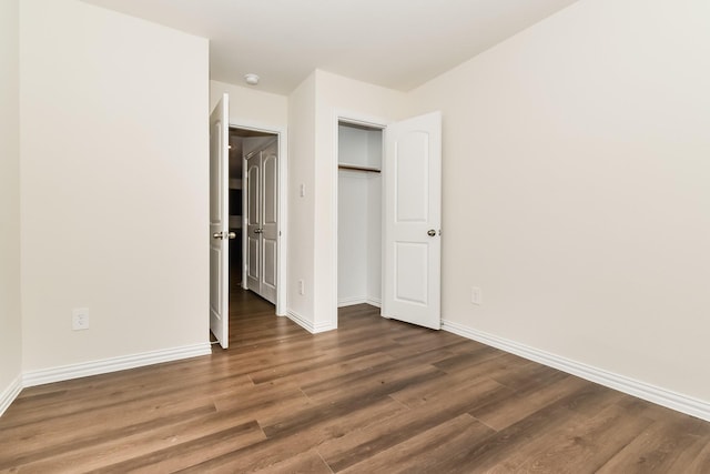 unfurnished bedroom with baseboards, wood finished floors, and a closet