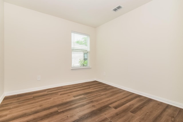 spare room featuring baseboards, lofted ceiling, dark wood finished floors, and visible vents
