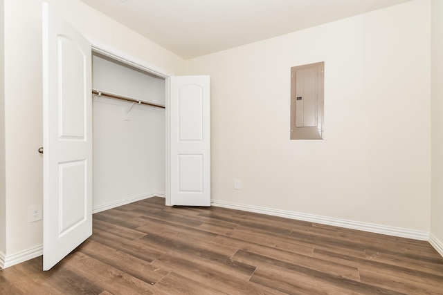 unfurnished bedroom featuring baseboards, electric panel, a closet, and dark wood-type flooring