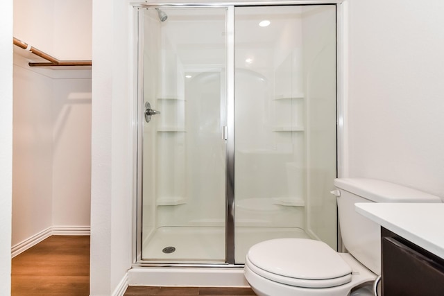 bathroom with a stall shower, wood finished floors, vanity, baseboards, and toilet