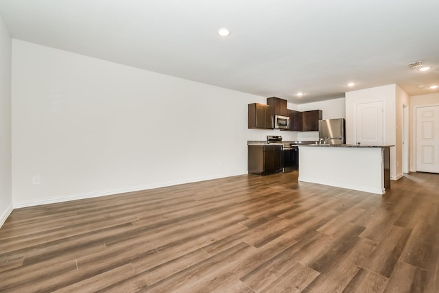 kitchen featuring dark wood-style flooring, stainless steel appliances, open floor plan, and dark brown cabinets