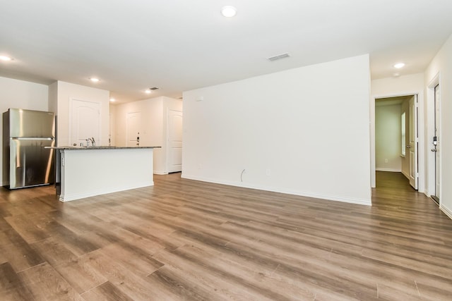 unfurnished living room with visible vents, dark wood finished floors, a sink, baseboards, and recessed lighting