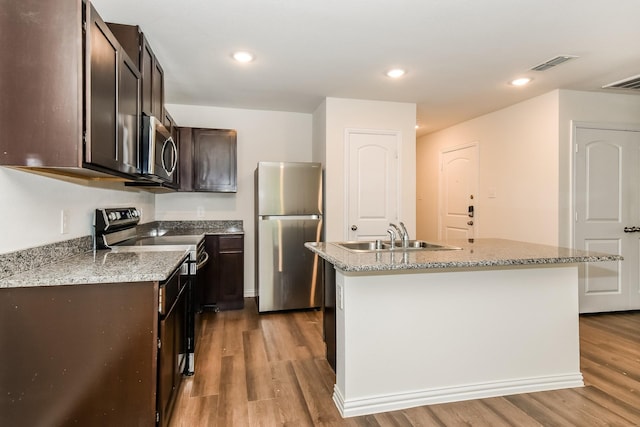 kitchen with dark brown cabinetry, visible vents, appliances with stainless steel finishes, a sink, and light wood finished floors