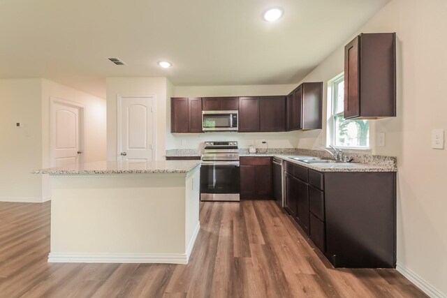 kitchen featuring a sink, light wood finished floors, appliances with stainless steel finishes, and dark brown cabinetry