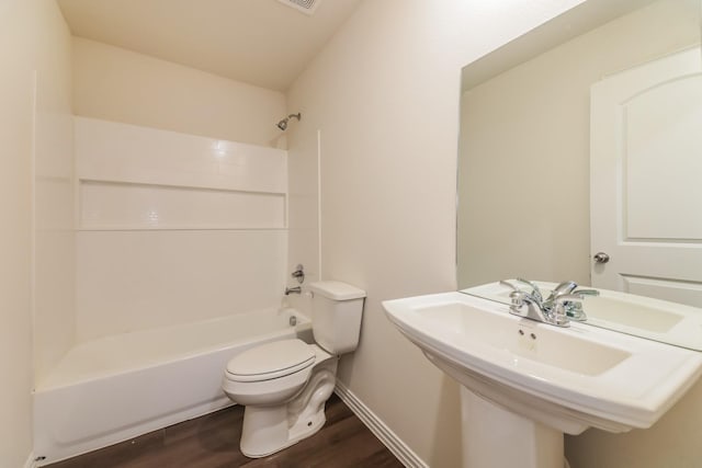 full bath with wood finished floors, toilet, baseboards, a sink, and shower / washtub combination